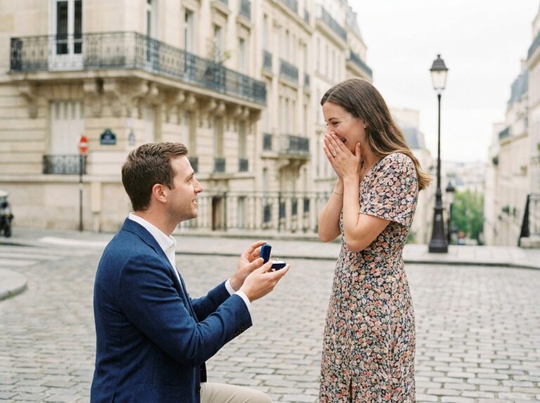 Homme agenouillé en train de faire une demande en mariage avec une bague de fiançailles sur une plaza pavée à Paris, femme surprise les mains sur la bouche